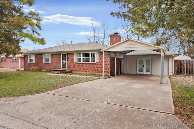 single story home featuring brick siding, fence, concrete driveway, french doors, and a front yard