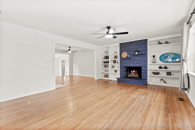 unfurnished living room with ceiling fan, light wood-type flooring, a fireplace, and built in features