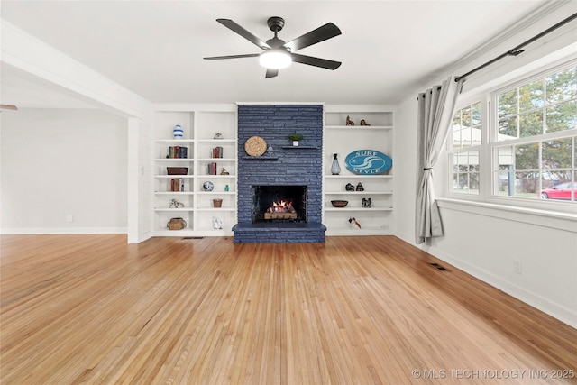 unfurnished living room with built in features, visible vents, a large fireplace, wood finished floors, and baseboards