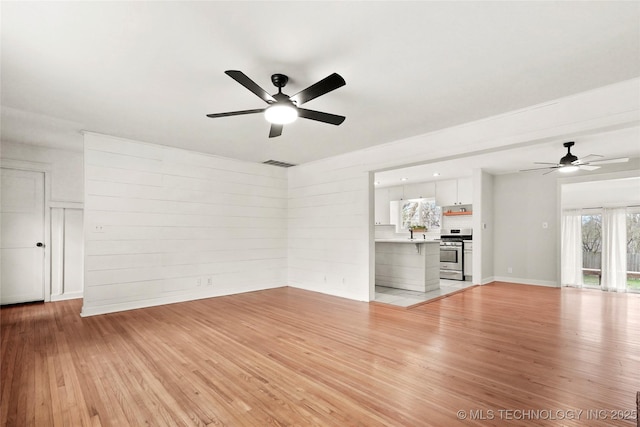 unfurnished living room featuring a ceiling fan, light wood-type flooring, visible vents, and baseboards