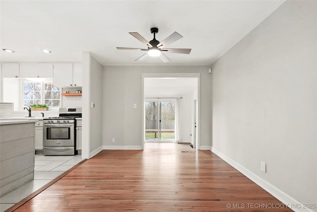 kitchen featuring stainless steel gas stove, plenty of natural light, light wood-style flooring, and backsplash