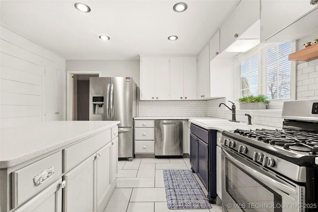 kitchen with white cabinets, decorative backsplash, stainless steel appliances, and a sink