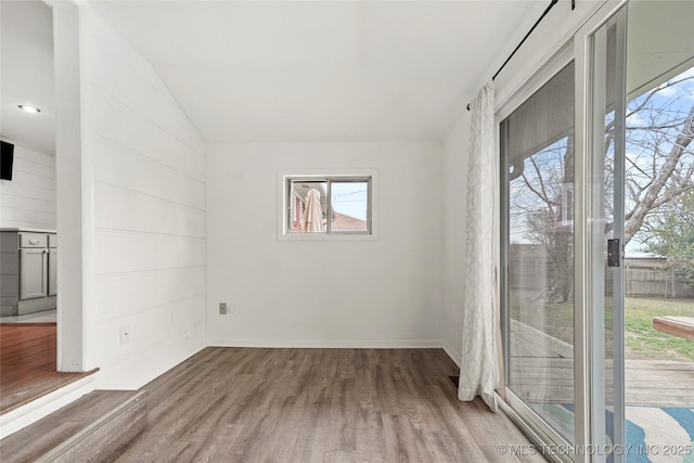 spare room with vaulted ceiling and wood finished floors