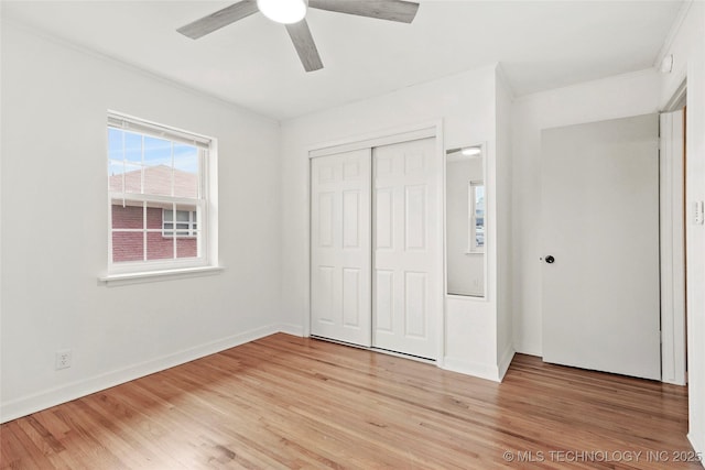 unfurnished bedroom featuring a closet, baseboards, crown molding, and light wood finished floors