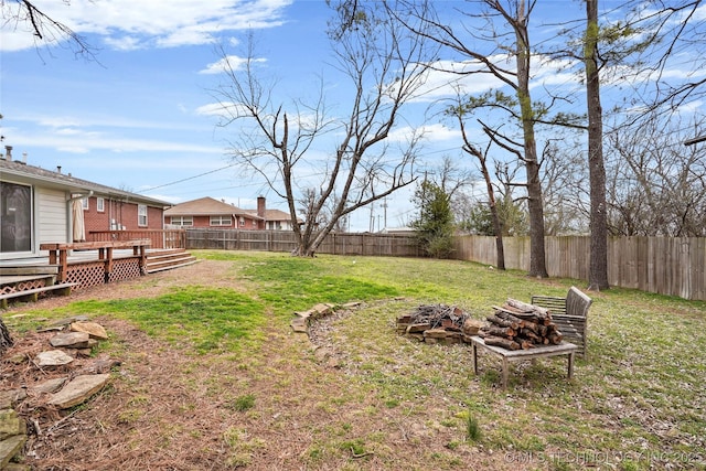 view of yard with a deck, an outdoor fire pit, and a fenced backyard