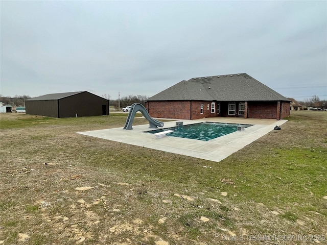 pool with an outbuilding, a yard, a water slide, and a patio