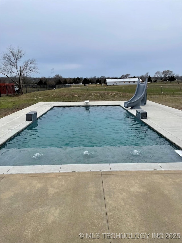 outdoor pool with a water slide and a lawn