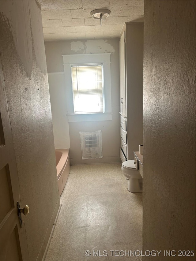 full bath featuring heating unit, a bathing tub, toilet, and tile patterned floors