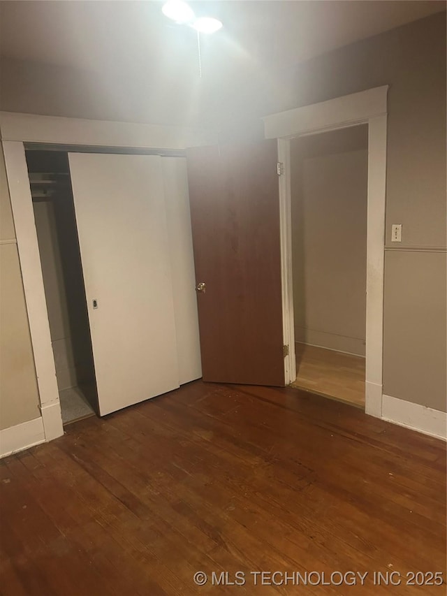 unfurnished bedroom with a closet, baseboards, and wood finished floors