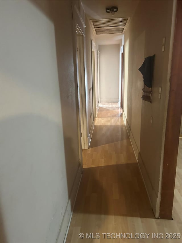 corridor with baseboards, visible vents, and wood finished floors