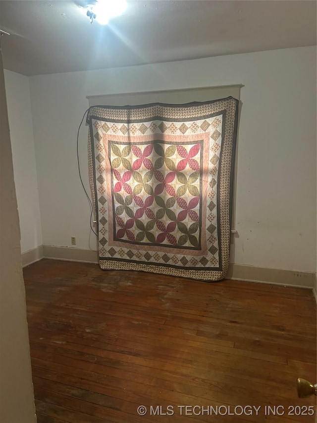 spare room featuring baseboards and hardwood / wood-style floors