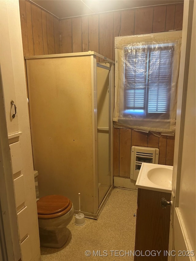 bathroom with a walk in shower, toilet, wooden walls, vanity, and heating unit