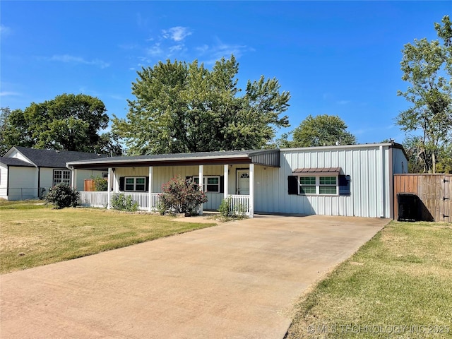 view of front facade with board and batten siding, a front yard, covered porch, and fence