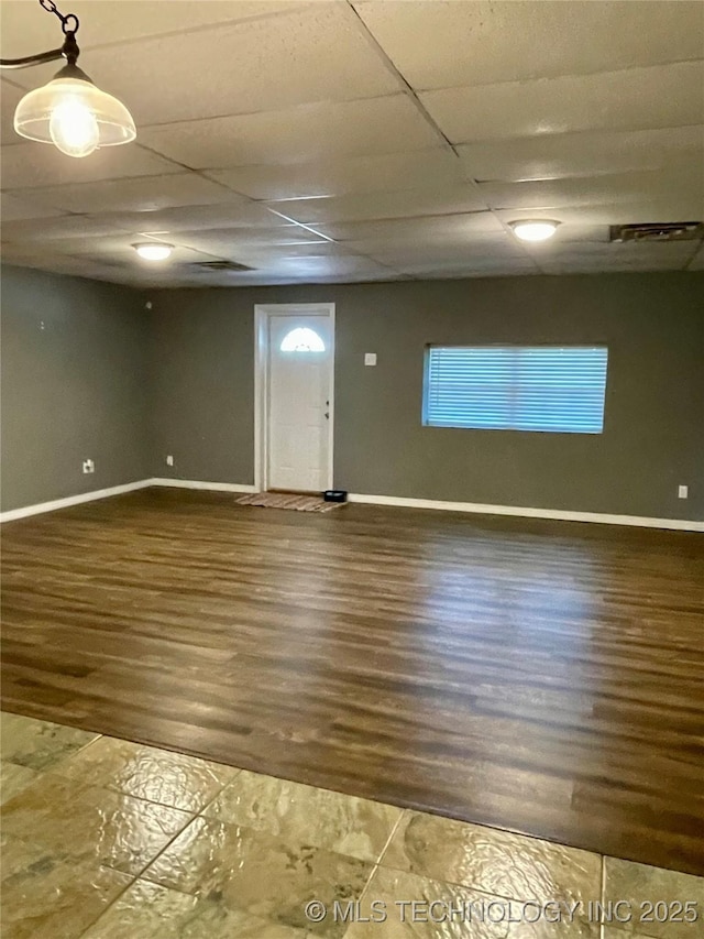 interior space with a drop ceiling, wood finished floors, visible vents, and baseboards