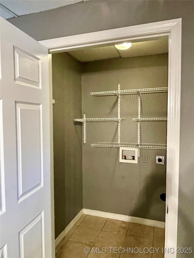 clothes washing area featuring laundry area, baseboards, tile patterned floors, hookup for an electric dryer, and washer hookup