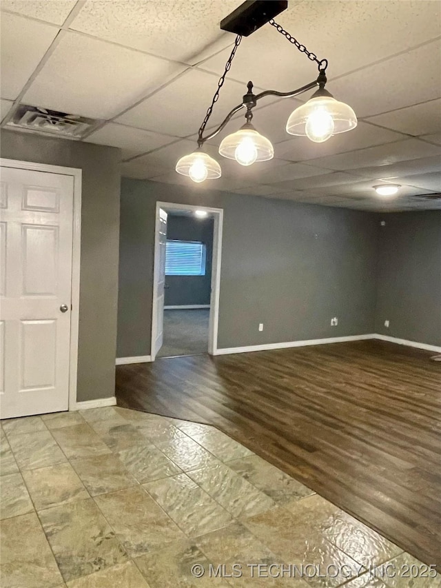 unfurnished room featuring baseboards, visible vents, and a drop ceiling