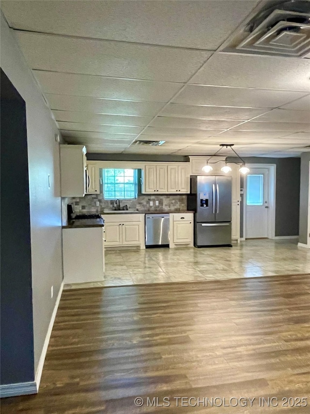 kitchen with tasteful backsplash, visible vents, dark countertops, appliances with stainless steel finishes, and a sink