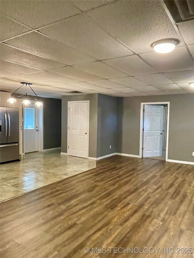 interior space featuring a drop ceiling, baseboards, and wood finished floors