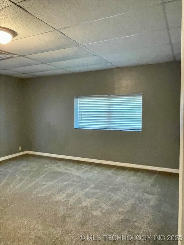 carpeted empty room with a drop ceiling and baseboards