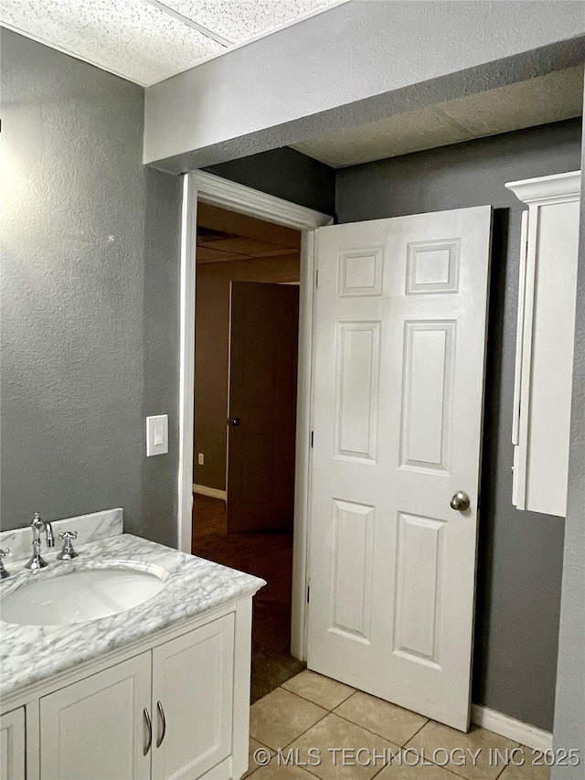 bathroom with vanity, baseboards, and tile patterned floors