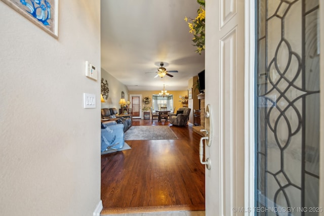 foyer entrance with dark wood finished floors and ceiling fan with notable chandelier