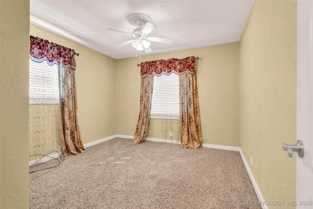 carpeted empty room featuring ceiling fan and baseboards