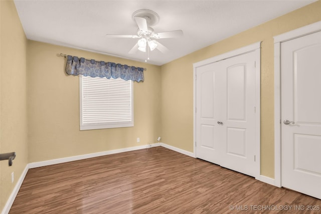 unfurnished bedroom featuring a ceiling fan, baseboards, and wood finished floors