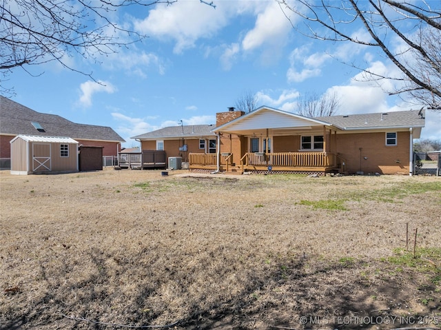 rear view of house featuring an outbuilding, brick siding, a chimney, central air condition unit, and a storage unit