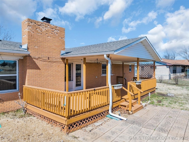 rear view of property featuring a shingled roof, fence, and brick siding