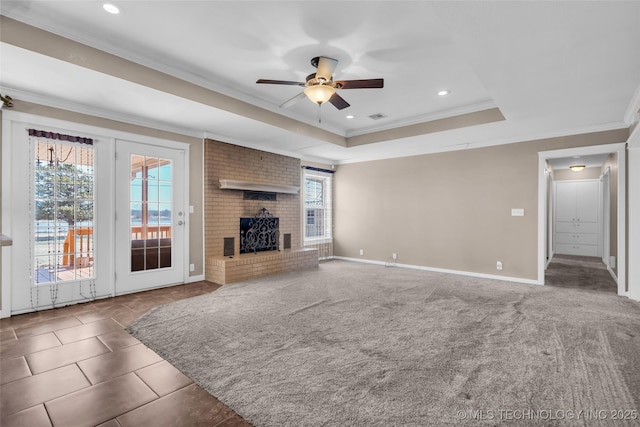 unfurnished living room featuring a fireplace, a raised ceiling, visible vents, ornamental molding, and baseboards