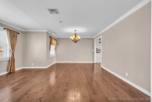 spare room with crown molding, wood finished floors, visible vents, and an inviting chandelier