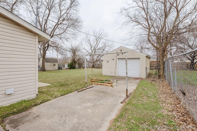 view of yard featuring an outbuilding, driveway, a detached garage, and fence