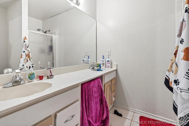 bathroom featuring a stall shower, tile patterned flooring, baseboards, and vanity