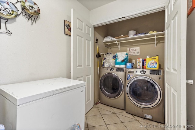 clothes washing area with laundry area, light tile patterned floors, and washer and clothes dryer