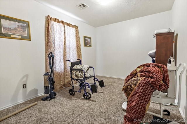 exercise area featuring carpet, visible vents, a textured ceiling, and baseboards