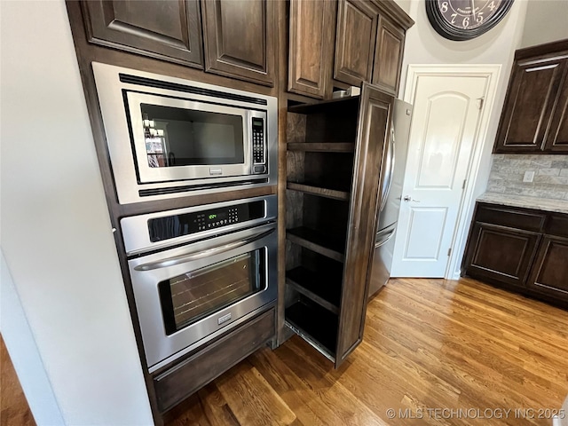 kitchen with open shelves, backsplash, appliances with stainless steel finishes, light wood-style floors, and dark brown cabinetry