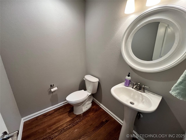 bathroom with wood finished floors, toilet, and baseboards