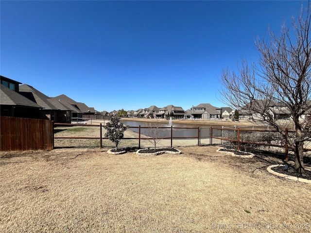 view of yard featuring a water view, fence, and a residential view