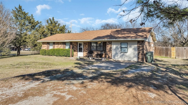 ranch-style home featuring a front yard, brick siding, and fence