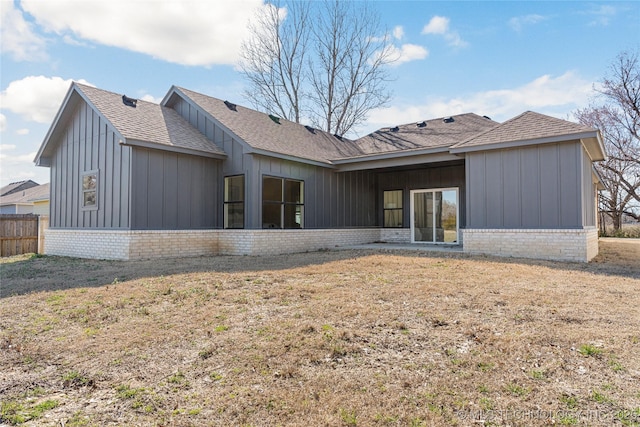 rear view of house featuring brick siding, board and batten siding, a shingled roof, and fence