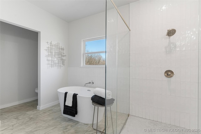 bathroom with a walk in shower, toilet, a freestanding bath, and tile walls