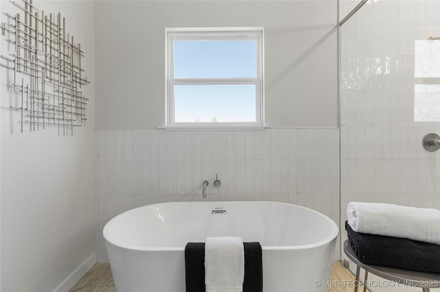 bathroom with a freestanding tub and tile walls