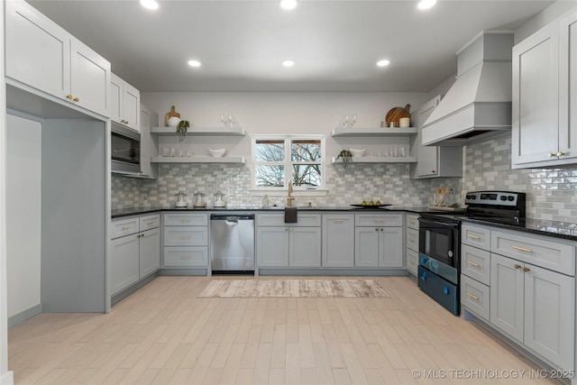 kitchen featuring open shelves, appliances with stainless steel finishes, dark countertops, and custom range hood