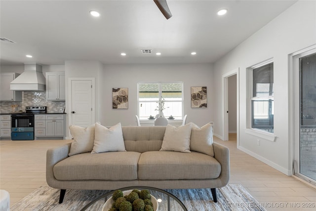 living room with baseboards, light wood-style flooring, visible vents, and recessed lighting