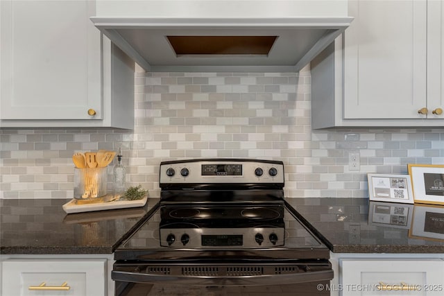 kitchen with electric range oven, tasteful backsplash, dark stone counters, and white cabinets