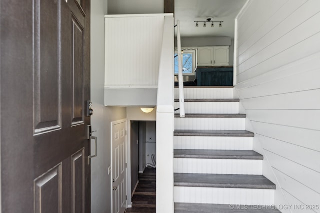 stairs with wooden walls and track lighting