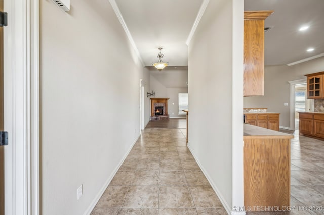 hallway with a healthy amount of sunlight, baseboards, ornamental molding, and light tile patterned flooring