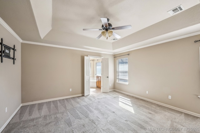 unfurnished bedroom with a tray ceiling, crown molding, visible vents, light carpet, and baseboards