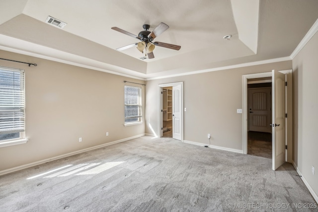 unfurnished bedroom with a raised ceiling, light carpet, crown molding, and visible vents