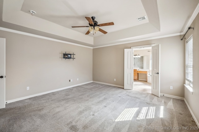 unfurnished bedroom with baseboards, visible vents, a tray ceiling, and crown molding